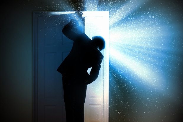 Person Opening a Door with Shining Light Coming Through its Opening