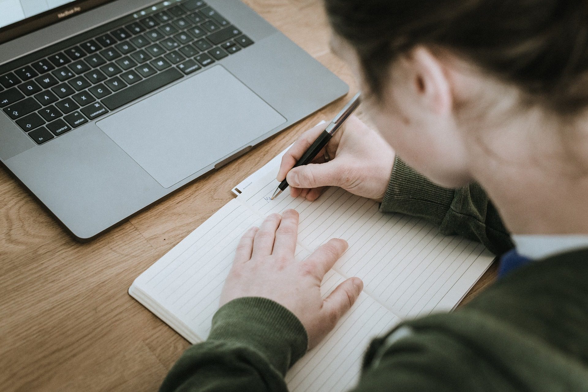 Woman Sitting at Desk Writing in a Notebook